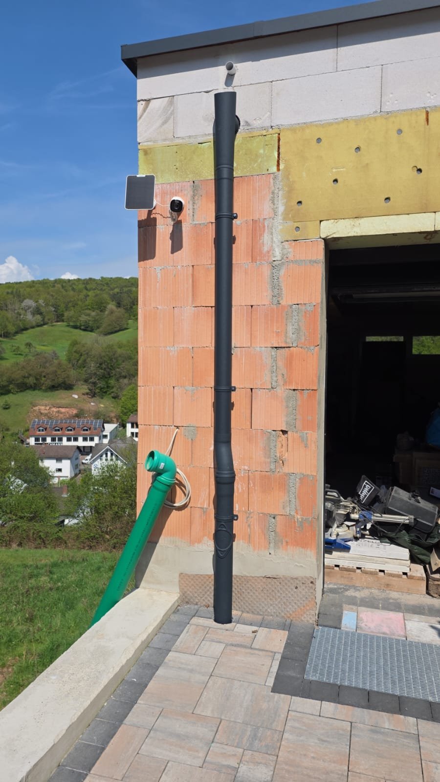 Neu montiertes Fallrohr einer Dachrinne am Rohbau in Johannesberg